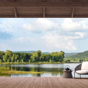 Panorama vista lago da una grande veranda in legno con pavimentazione in legno, una poltrona e un ta