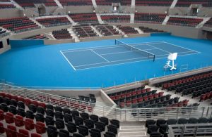 Un campo da tennis indoor completamente vuoto, visto dalle tribune, anch'esse senza spettatori