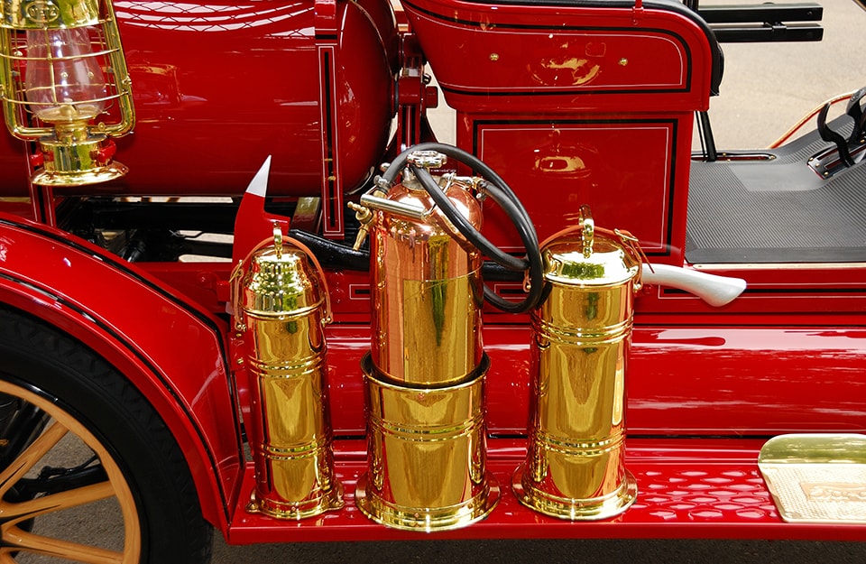 Primo piano di tre vecchi estintori antincendio in ottone esposti su un'antica autopompa