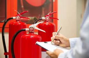 Un addetto con una cartellina in mano esamina un gruppo di estintori antincendio