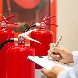 Un addetto con una cartellina in mano esamina un gruppo di estintori antincendio