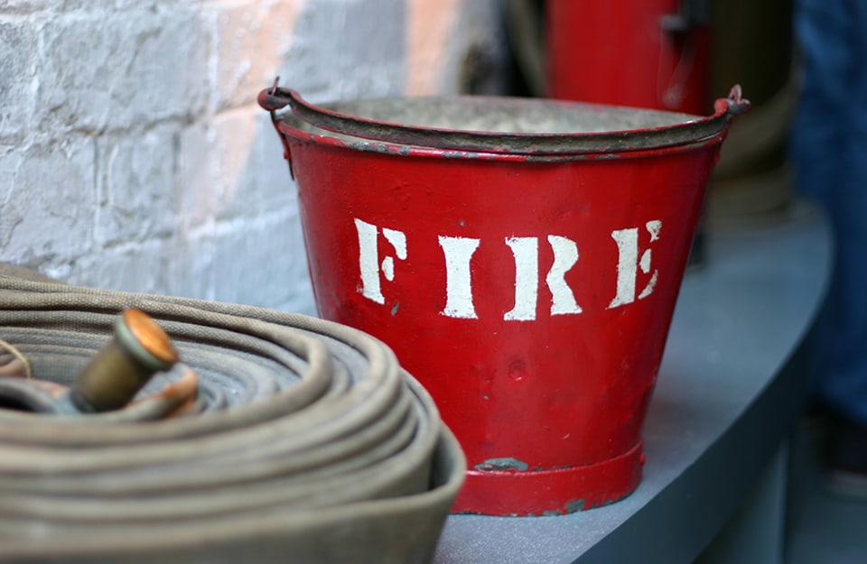 Un vecchio secchio dei pompieri di colore rosso e con la scritta “Fire”