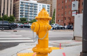 Un idrante di colore giallo in primo piano in un'area urbana