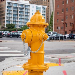 Un idrante di colore giallo in primo piano in un'area urbana