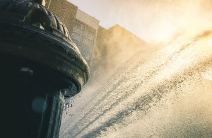 Primo piano su un tombino aperto che schizza acqua per alleviare le sofferenze dovute all'afa