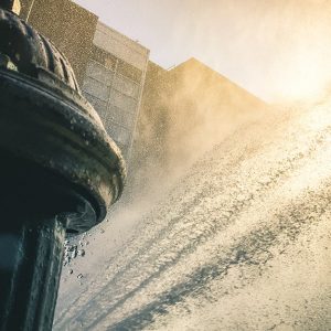 Primo piano su un tombino aperto che schizza acqua per alleviare le sofferenze dovute all'afa