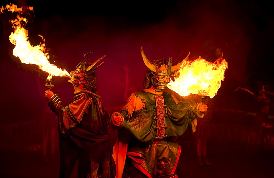 Spettacolo teatrale con attori vestiti da demoni che mangiano il fuoco