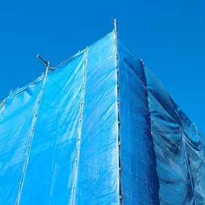 Palazzo con impalcatura coperta di colore azzurro, sullo sfondo di un cielo pure azzurro