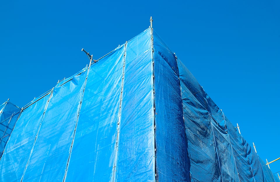Palazzo con impalcatura coperta di colore azzurro, sullo sfondo di un cielo pure azzurro