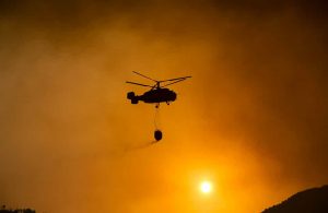 Silhouette di un elicottero dei pompieri in azione durante un incendio boschivo