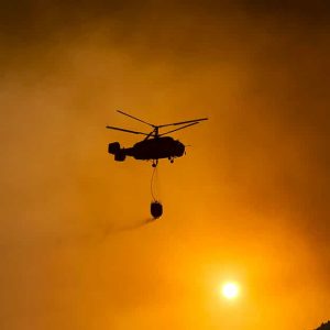 Silhouette di un elicottero dei pompieri in azione durante un incendio boschivo