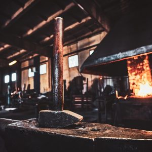 Ricostruzione dell'interno di un'officina medievale di un fabbro, con in primo piano un martello a testa in giù sopra un'incudine