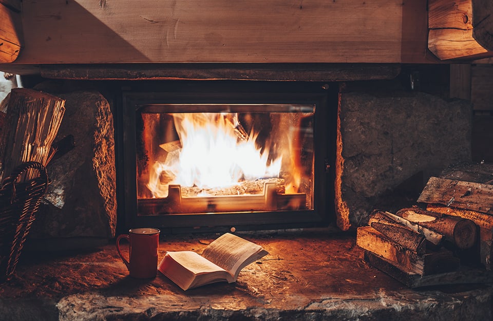 Un camino acceso con un libro aperto davanti al fuoco