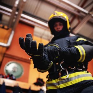Un vigile del fuoco in caserma vestito con tutto l'equipaggiamento, casco compreso, si infila i guanti