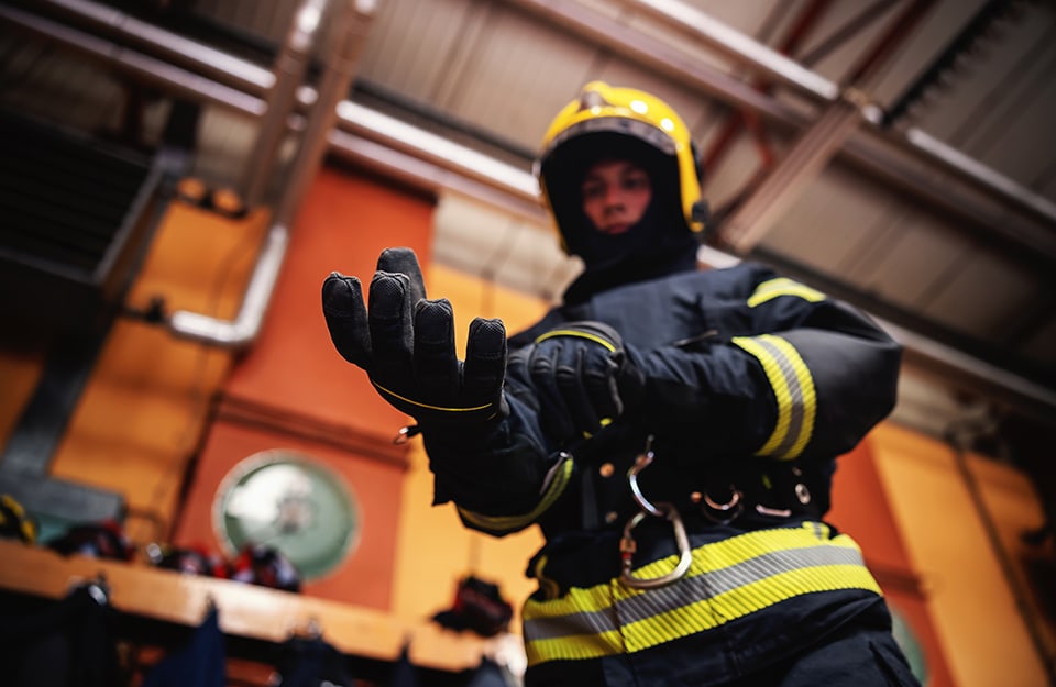 Un vigile del fuoco in caserma vestito con tutto l'equipaggiamento, casco compreso, si infila i guanti