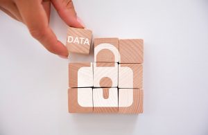 Una mano aggiunge un cubetto in legno con su scritto “data” a una serie di 8 cubetti in legno che formano il disegno di un lucchetto