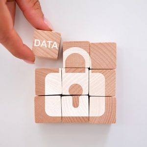 Una mano aggiunge un cubetto in legno con su scritto “data” a una serie di 8 cubetti in legno che formano il disegno di un lucchetto