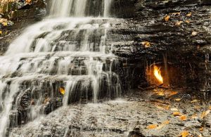 Vista della fiamma all'interno della grotta sovrastata dalla cascata delle Eternal Flame Falls, negli Stati Uniti