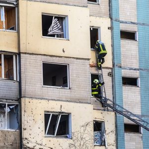 Due pompieri ucraini salgono con una scala dentro alle finestre di un palazzo colpito dai razzi russi a Kyev durante la guerra in Ucraina del 2022