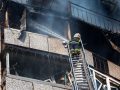 Un pompiere ucraino spegne un incendio da una scala in un palazzo di Kyev colpito dai razzi russi durante la guerra in Ucraina del 2022