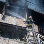 Un pompiere ucraino spegne un incendio da una scala in un palazzo di Kyev colpito dai razzi russi durante la guerra in Ucraina del 2022