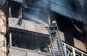 Un pompiere ucraino spegne un incendio da una scala in un palazzo di Kyev colpito dai razzi russi durante la guerra in Ucraina del 2022