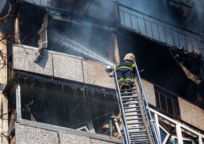 Un pompiere ucraino spegne un incendio da una scala in un palazzo di Kyev colpito dai razzi russi durante la guerra in Ucraina del 2022