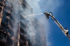 Alcuni pompieri sparano acqua da un'autoscala su un palazzo in fiamme dopo essere stato colpito dall'artiglieria russa a Kyev, durante la guerra in Ucraina