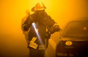 Pompiere interviene durante un incendio in galleria in mezzo a un'aria densa di fumo e illuminata da luci gialle