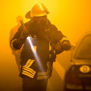Pompiere interviene durante un incendio in galleria in mezzo a un'aria densa di fumo e illuminata da luci gialle