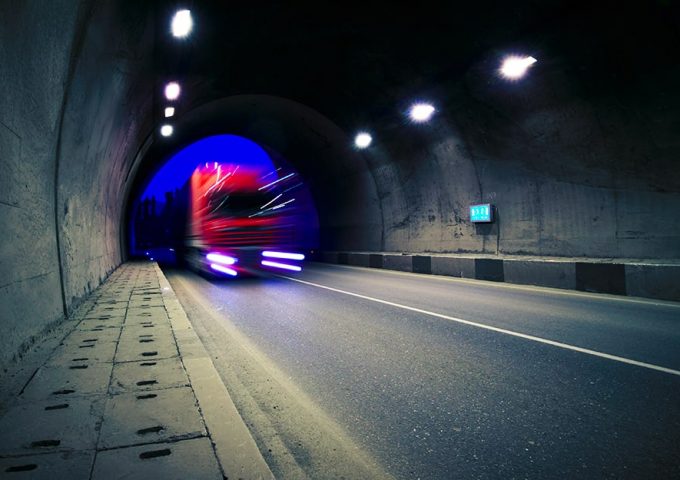 Un camion rosso entra in velocità dentro a una galleria. Il soggetto è mosso mentre lo sfondo non lo è