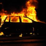 Silhouette di un'auto in fiamme, di notte, vista di lato