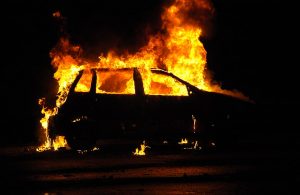 Silhouette di un'auto in fiamme, di notte, vista di lato