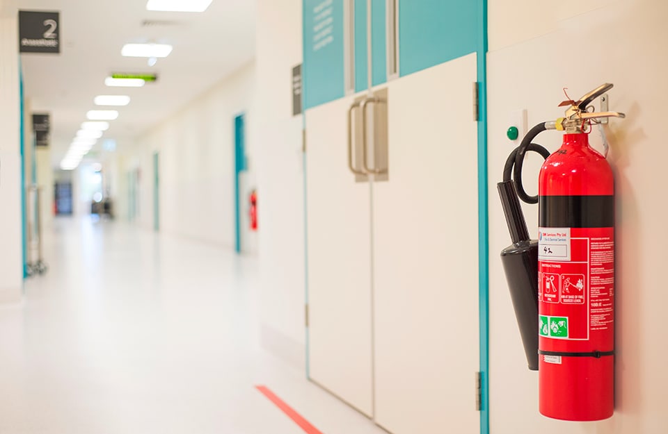Una corsia d'ospedale vuota con in primo piano un estintore rosso