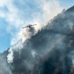 Un Canadair visto frontalmente mentre vola lungo il pendio della montagna sopra il lago di Ghirla, in provincia di Varese, durante un incendio boschivo