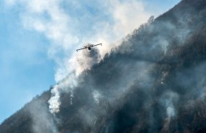 Un Canadair visto frontalmente mentre vola lungo il pendio della montagna sopra il lago di Ghirla, in provincia di Varese, durante un incendio boschivo