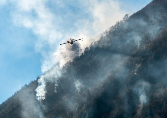Un Canadair visto frontalmente mentre vola lungo il pendio della montagna sopra il lago di Ghirla, in provincia di Varese, durante un incendio boschivo