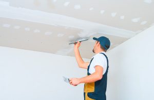 Un operaio sta lavorando a un controsoffitto in cartongesso con una spatola