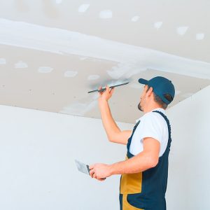 Un operaio sta lavorando a un controsoffitto in cartongesso con una spatola