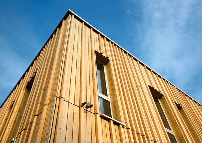 Vista dal basso di due facciate di un edificio in legno costruito secondo i principi della bioedilizia
