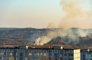 Un incendio di erba secca in un'area d'interfaccia urbana, tra palazzi di periferia e abitazioni sulle colline