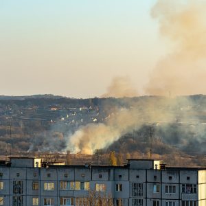 Un incendio di erba secca in un'area d'interfaccia urbana, tra palazzi di periferia e abitazioni sulle colline