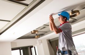 Un tecnico sta installando un rilevatore di fumi sul soffitto di una stanza