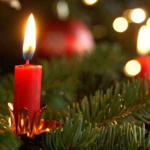 Dettaglio di un abete natalizio con delle candele rosse accese installate