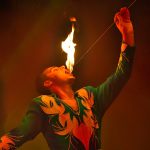 Esibizione di un mangiafuoco del circo, che si sta mettendo in bocca un bastone con una fiamma