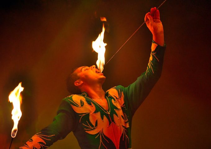 Esibizione di un mangiafuoco del circo, che si sta mettendo in bocca un bastone con una fiamma