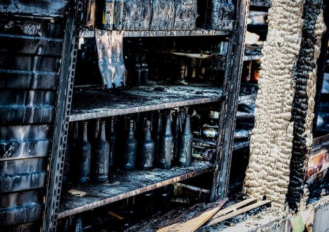 Scaffale pieno di bottiglie completamente arso da un incendio