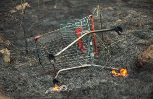 Un carrello della spesa rotto e in fiamme su un campo bruciato