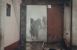 Tre pompieri peruviani durante un intervento in un vecchio edificio invaso dal fumo