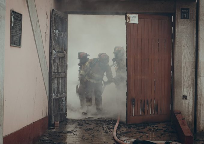 Tre pompieri peruviani durante un intervento in un vecchio edificio invaso dal fumo